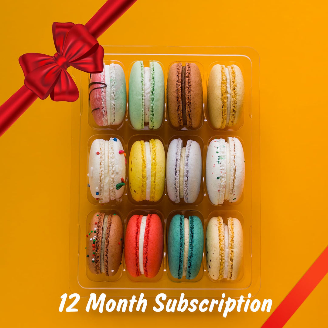 Box of colorful macarons with a red ribbon on an orange background, labeled '12 Month Subscription'.