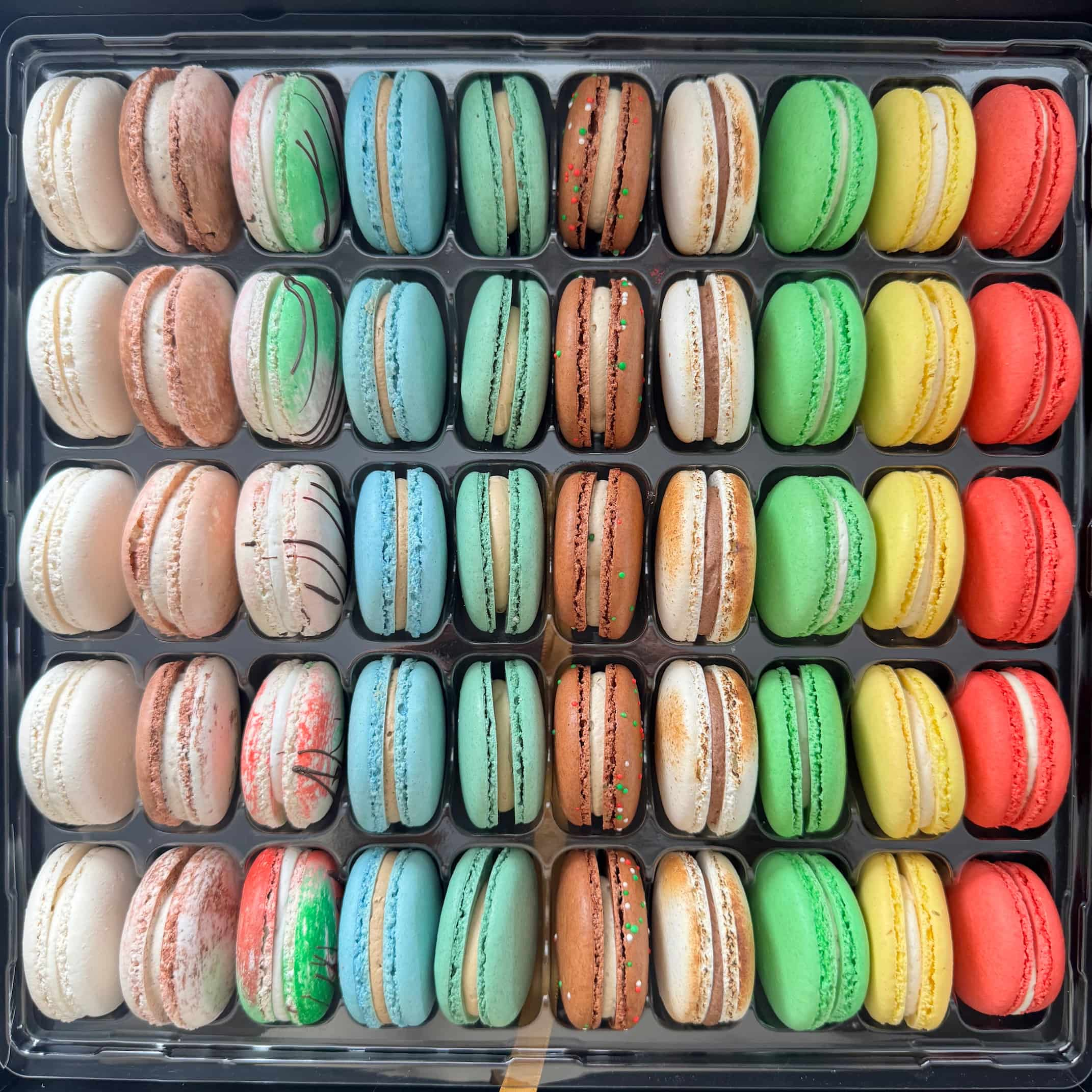 a variety of 10 different flavors lined up in a 50 pack of french macarons