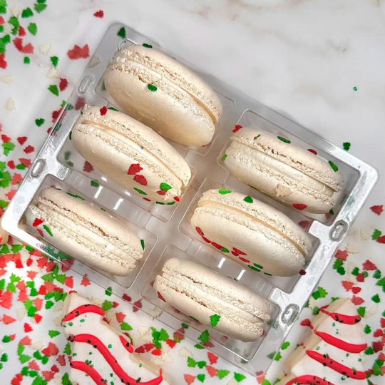 Six christmas tree cake flavors macarons surrounded by red and green sprinkles