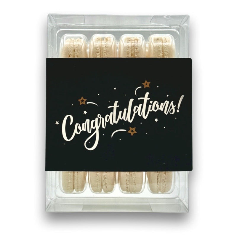 a 12 pack box of macarons wrapped in a sleeve that says congratulations in script
