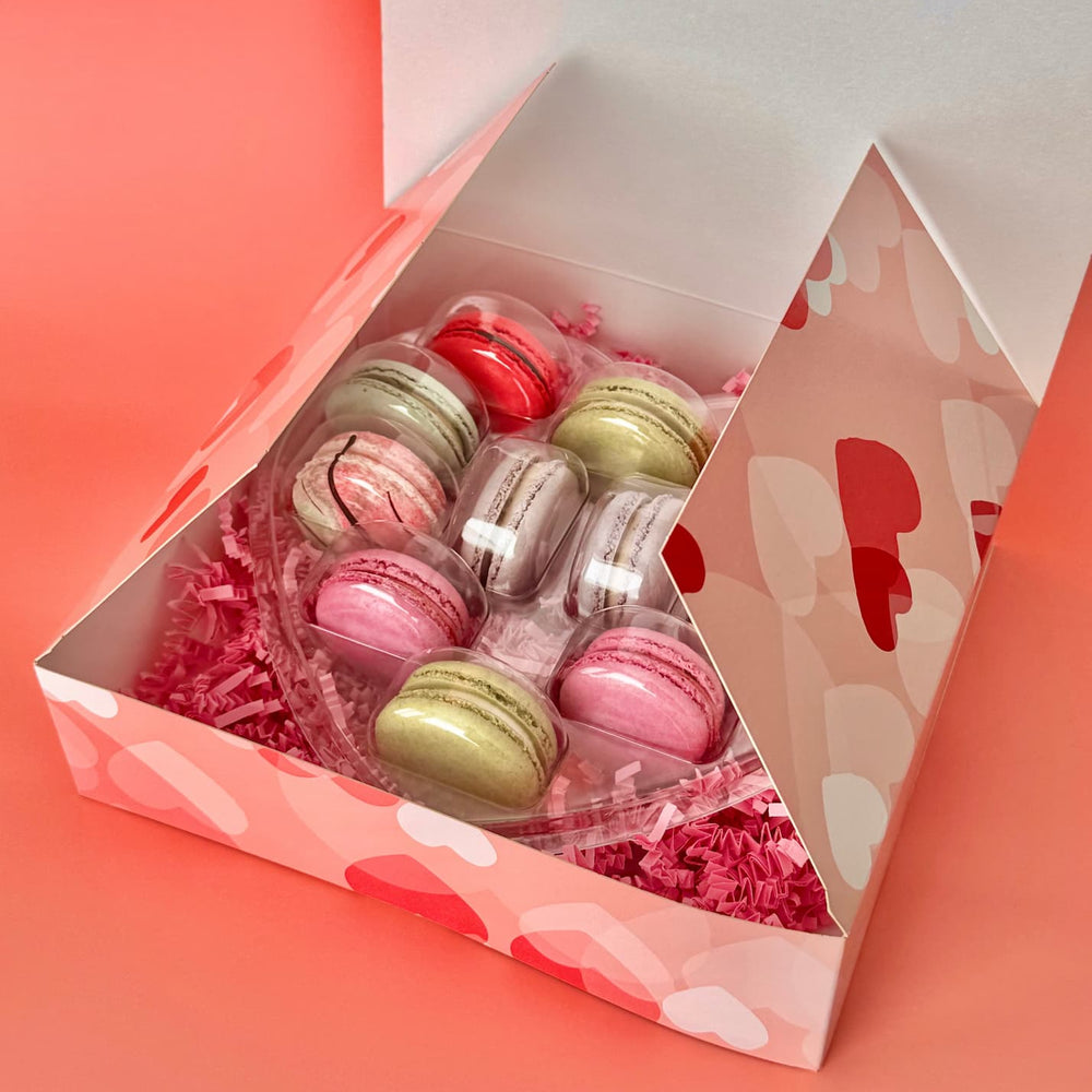 a heart shaped pack of 12 French macarons sitting in a box