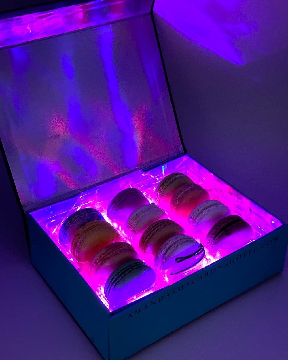 A glowing, pink LED box with macarons inside, presented as a gift.