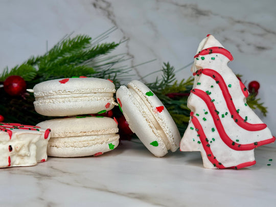 Christmas tree cake french macarons surrounded by actual christmas tree cakes and some decorations